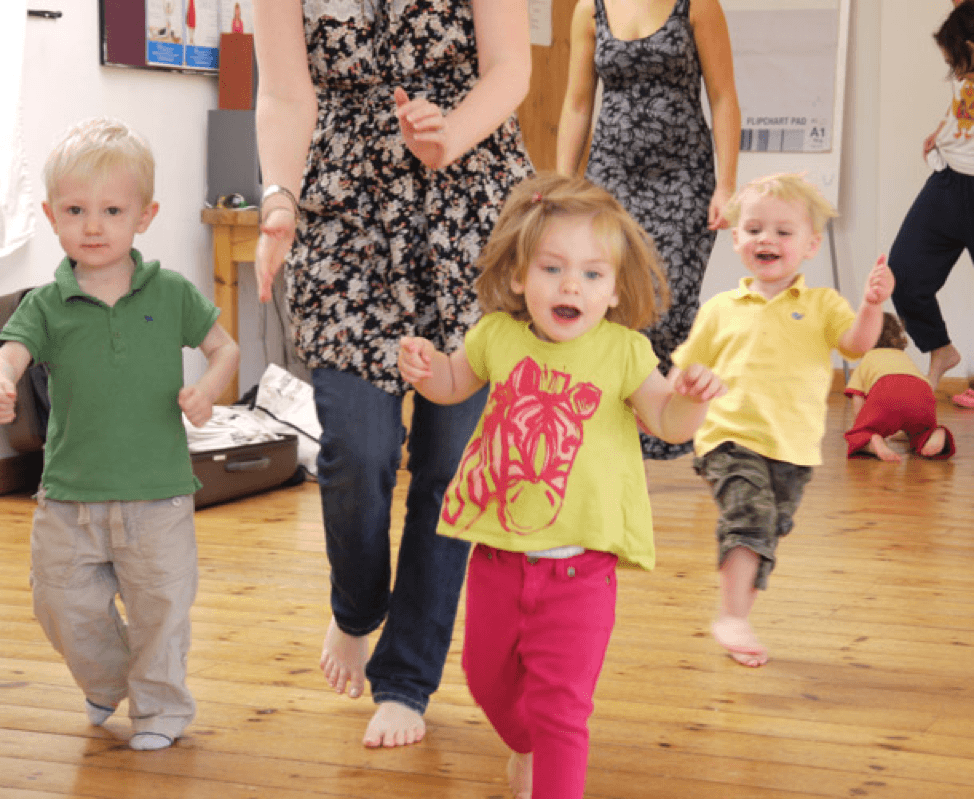 Children walking around with their moms in a classroom setting