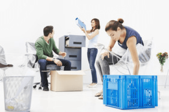 Man, wearing a green sweater and two women are packing up an office space