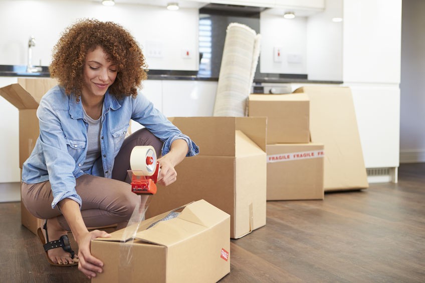 Lady wearing a blue shirt taping up boxes to move her belongings