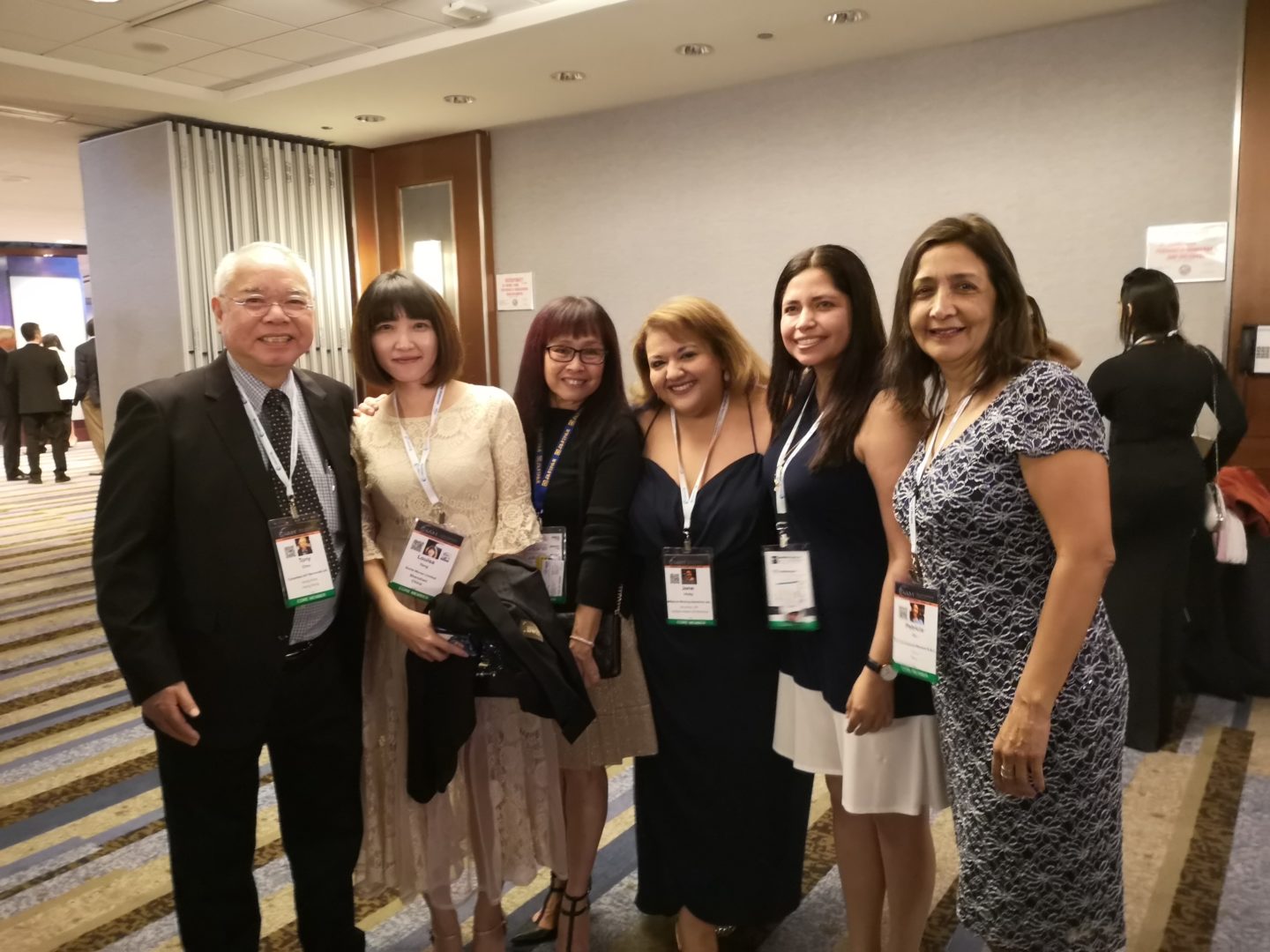 Man, in a suit with five women dressed up at a conference